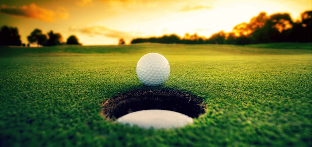 Golf ball on the edge of a hole at sunset on a lush golf course green in Maroochydore, Sunshine Coast.
